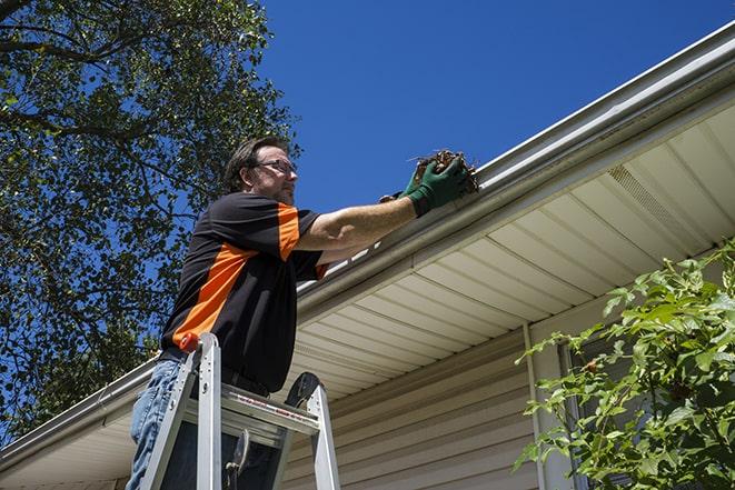 a skilled worker fixing broken gutter on a roof in Palmyra